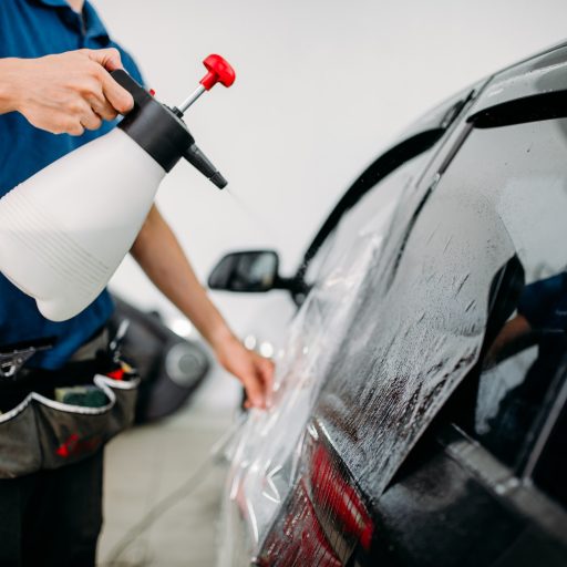 Male hand with spray, car window tint installation